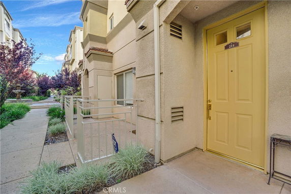 Front view of a townhouse with a yellow door and small gated area.