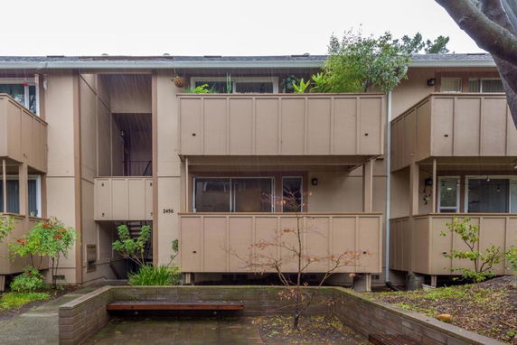 Front view of a multi-story apartment building with balconies and staircase access.