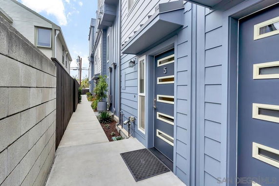 Side view of a townhouse with blue siding and modern entry doors.