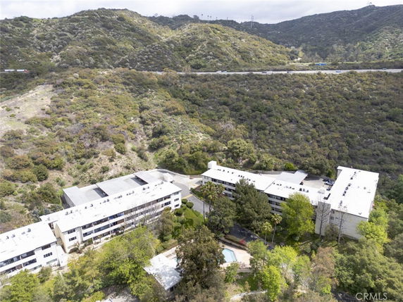 Aerial view of a complex of buildings surrounded by hills and greenery.