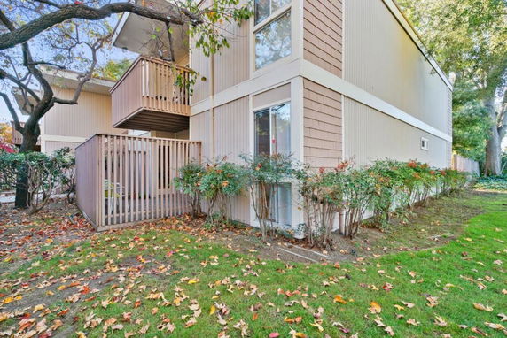 Corner view of a two-story residential building with wooden balcony railings.