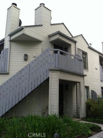 Front view of a multi-story house with external stairs and chimneys.