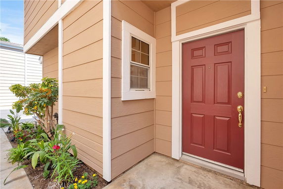 Front view of an entryway with a red door and beige siding.