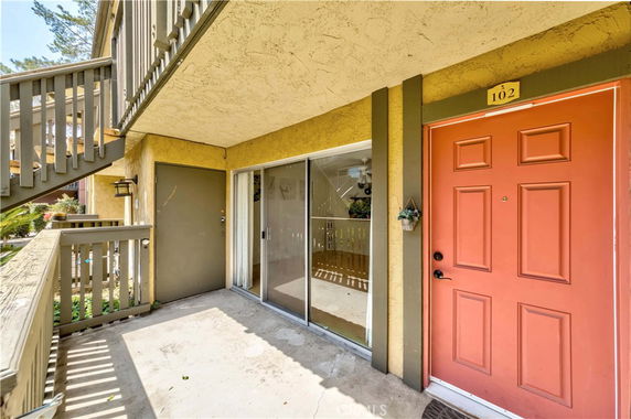 Front view of a ground-floor apartment with red door and sliding glass door.