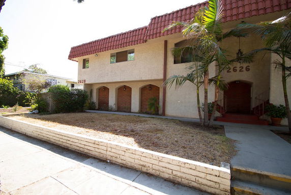 Front view of a two-story building with red-tiled roof and arched entrances.
