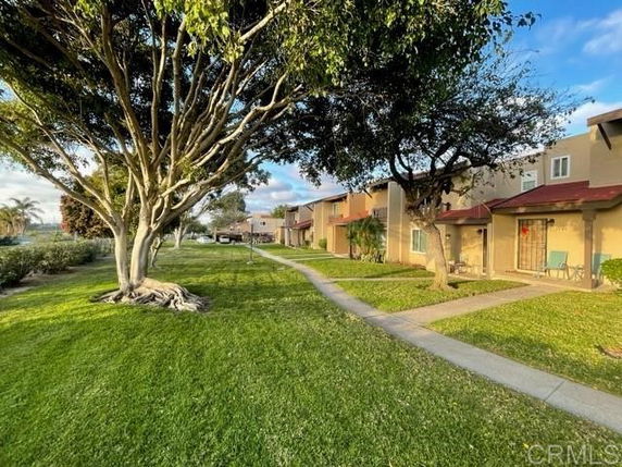 View of residential buildings with a lawn and walkway.