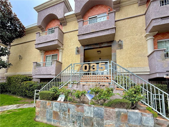 Front view of a multi-story apartment building with decorative entrance and balconies.