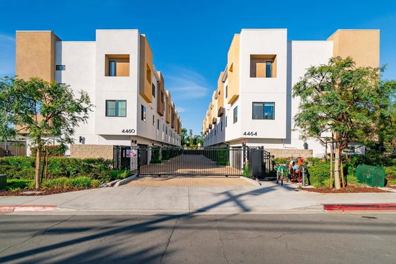 Front view of modern multi-story apartment buildings with a gated entrance.