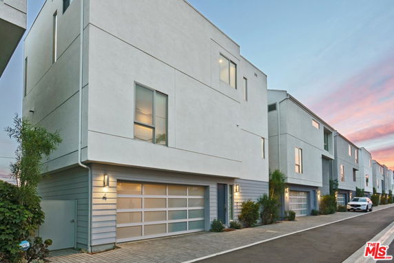 Front view of a series of modern multi-story townhouses with large windows and garages.