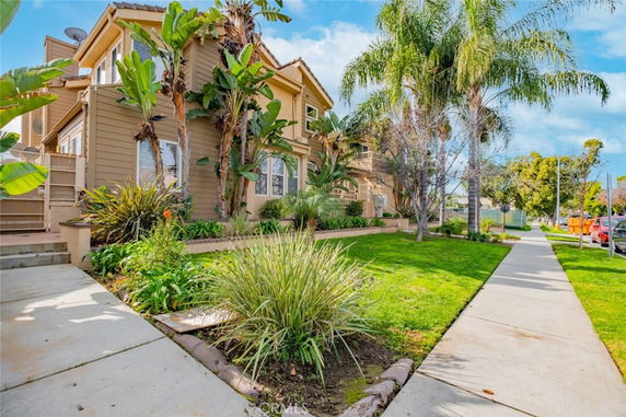 Front view of a multi-story house with a well-maintained garden and palm trees.