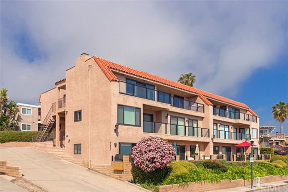 Front view of a multi-story building with balconies and red-tiled roof.