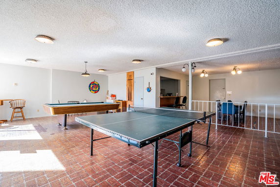 Recreational area with pool and ping pong tables inside a clubhouse.
