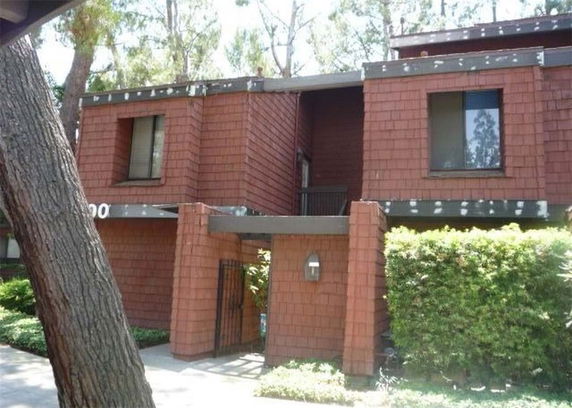 Front view of a multi-story house with brick exterior and large windows.