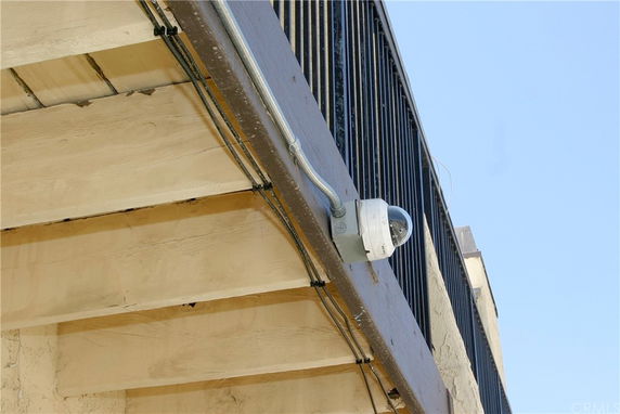 Underside view of a building's exterior with metal railing and surveillance camera.