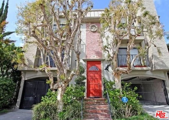 Front view of a building with a red entrance door and brick facade.