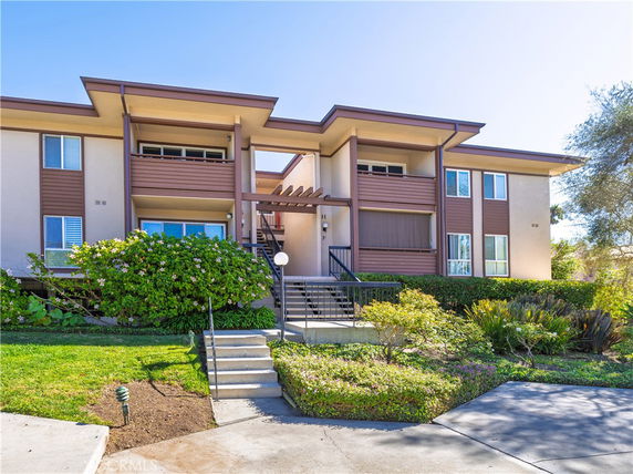 Front view of a two-story apartment building with brown accents and stair entrance.