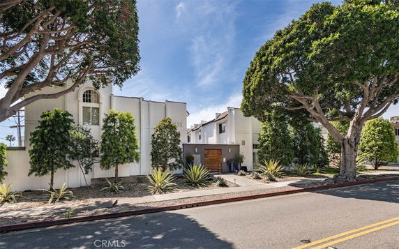 Front view of a modern two-story house with white exterior and a wooden gate.
