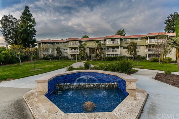 View of a multi-story residential building with a fountain in the foreground.