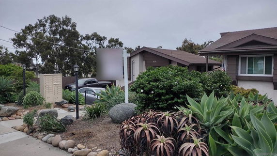 Front view of a house with a sloping roof and surrounding greenery.