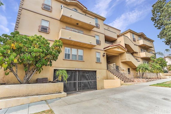 Front view of a multi-story residential building with balconies and an entrance.