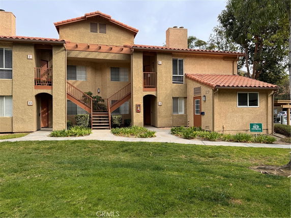 Front view of a two-story apartment building with a central staircase and beige exterior.