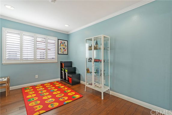 A room with a colorful play mat, shelves, and a glass cabinet, suitable for children's activities.