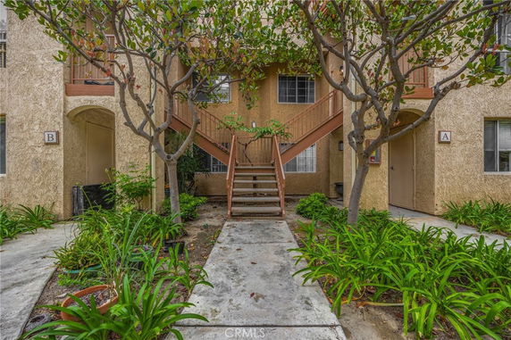 Front view of a multi-story apartment building with staircases and a garden area.