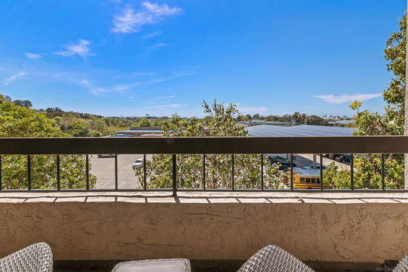 Panoramic view from a balcony showing distant landscape and a parking area.