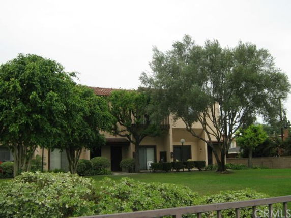 Front view of a two-story building with arched entryways and surrounding trees.