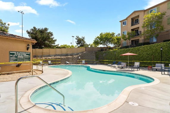 Outdoor swimming pool with lounge chairs and a building in the background.