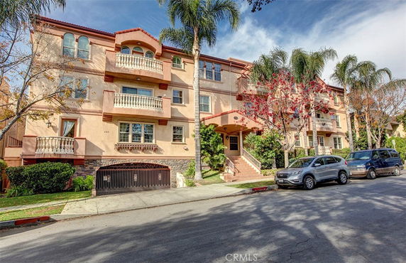 Front view of a multi-story residential building with balconies and an underground parking entrance.