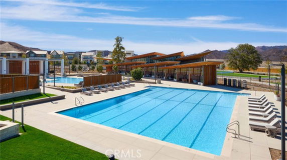 Outdoor swimming pool area with lounge chairs and modern building structure.
