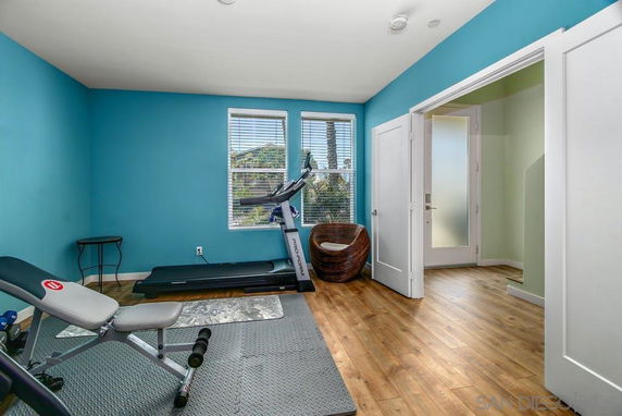Room with exercise equipment including a treadmill and bench.