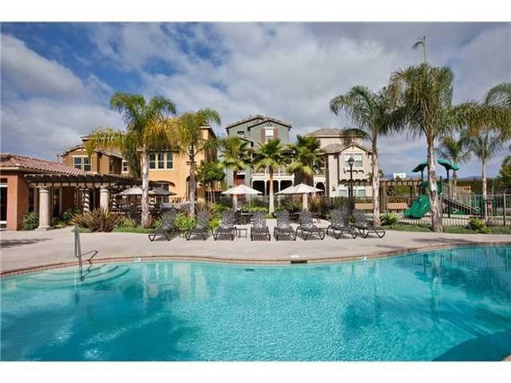 Outdoor swimming pool area with lounge chairs and palm trees at a residential property.