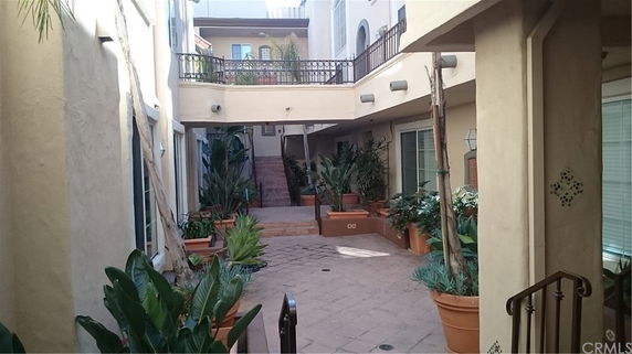 Courtyard view with potted plants and a two-story building.
