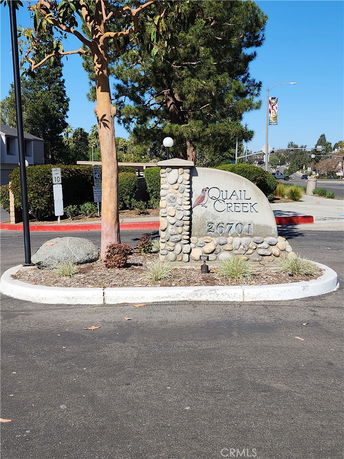 Entrance sign with stone facade and surrounding trees.