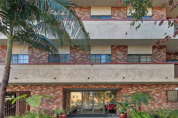 Front view of a multi-story building with brick facade and glass entrance.