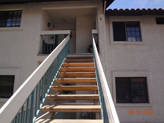 Front view of a two-story building with an external staircase leading up to a second-floor entrance.