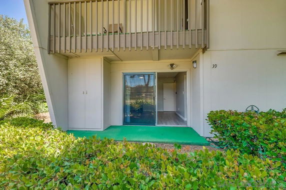 Front view of a building with a balcony and sliding glass door entry.