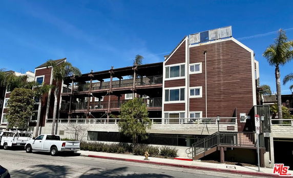 Front view of a multi-story apartment building with wood paneling and balconies.