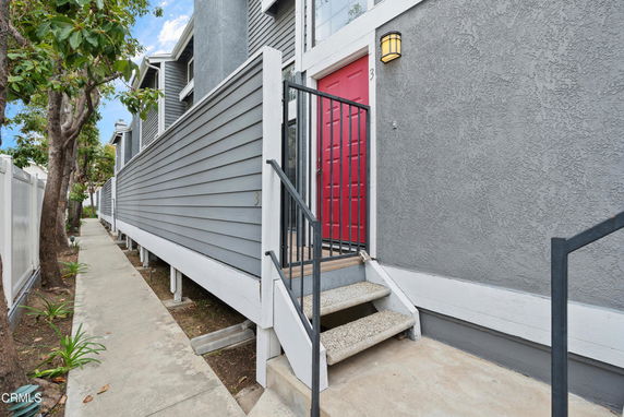 Front view of a house with gray exterior and red door.