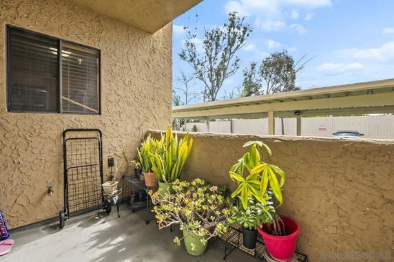 Outdoor patio area with plants and a view of a parking structure.