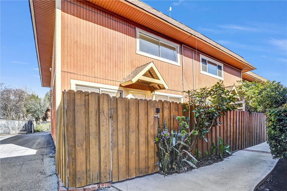 Front view of a two-story house with wooden exterior and a fenced yard.