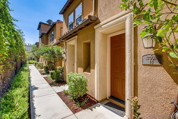 Front view of a two-story townhouse with beige and brown exterior walls and a pathway leading to the entrance.
