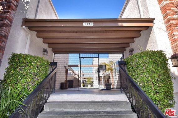Front view of a multi-story building entrance with a gated entry and stairway.