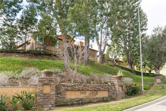 Front view of a residential building on a hill with surrounding trees.