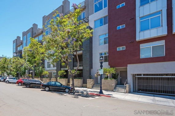 Front view of a multi-story apartment building with multiple balconies and a garage entrance.