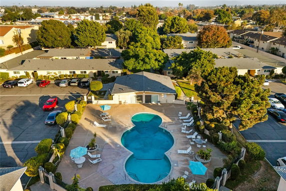 Aerial view of a swimming pool area surrounded by residential buildings and parked cars.