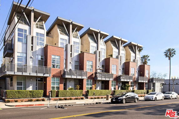 Front view of a modern multi-story apartment building with brick and metal facade.