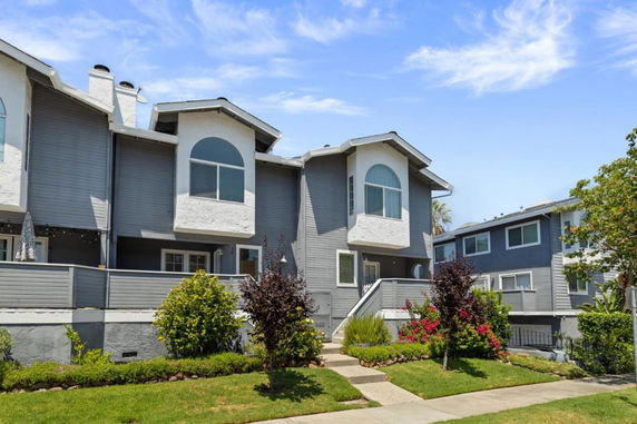 Front view of a multi-story townhouse with large windows and a small front yard.